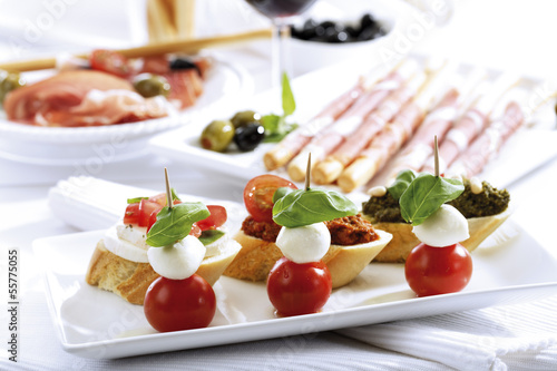 Photo: Grissini mit Parmaschinken und Oliven und Mozzarella mit Tomaten, italienische Vorspeisen Grissini mit Parmaschinken und Oliven und Mozzarella mit Tomaten, italienische Vorspeisen