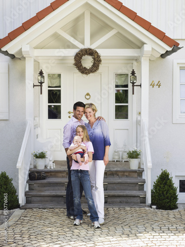 Photo: Familie mit Baby stehend vor Eigenheim Familie mit Baby stehend vor Eigenheim