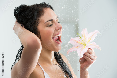 Photo: Woman washing herself with happy smile, lily flower and water sp Woman washing herself with happy smile, lily flower and water sp