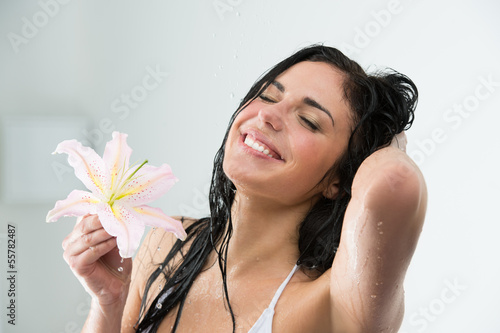 Photo: Woman washing herself with happy smile, lily flower and water sp Woman washing herself with happy smile, lily flower and water sp
