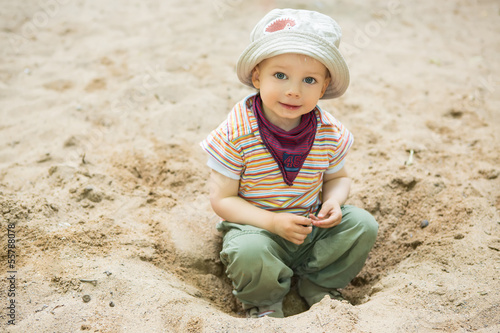 Photo: Kind sitzt im Sand auf dem Spielplatz Kind sitzt im Sand auf dem Spielplatz