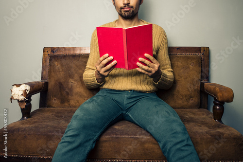 Photo: Young man reading on old sofa Young man reading on old sofa