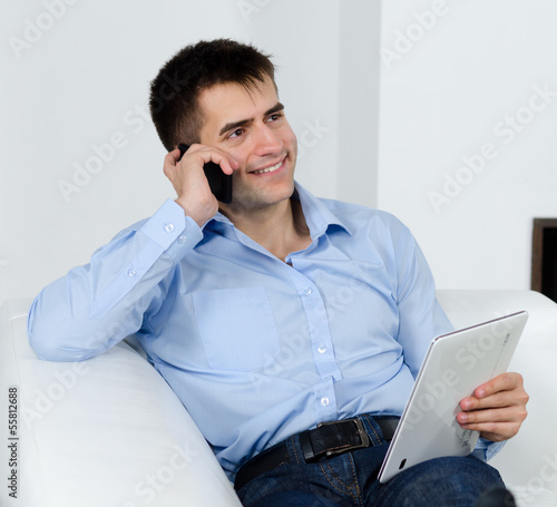 Photo: freundlicher mann mit tablet am telefon freundlicher mann mit tablet am telefon