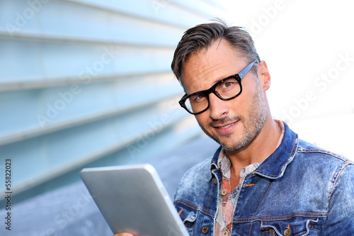 Photo: Man with blue jeans jacket using digital tablet Man with blue jeans jacket using digital tablet