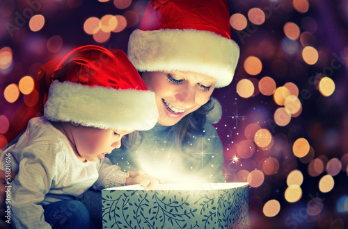 Photo: Christmas magic gift box and a happy family mother and baby Christmas magic gift box and a happy family mother and baby