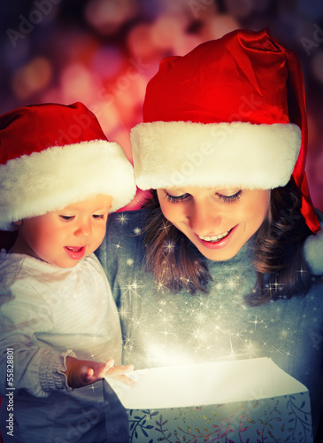 Photo: Christmas magic gift box and a happy family mother and baby Christmas magic gift box and a happy family mother and baby