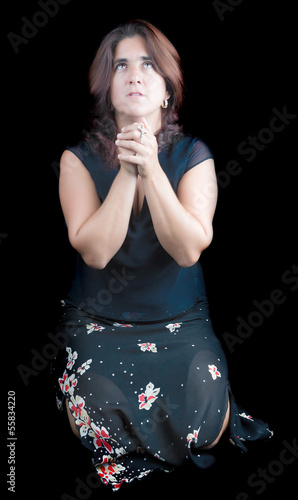 Photo: Latin woman praying and holding a small crucifix Latin woman praying and holding a small crucifix