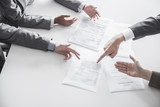 Photo: Four business people arguing and gesturing around a table during a business meeting, hands only Four business people arguing and gesturing around a table during a business meeting, hands only