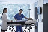 Photo: Female doctor and nurse wheeling a stretcher with a patient in the halls of the hospital Female doctor and nurse wheeling a stretcher with a patient in the halls of the hospital