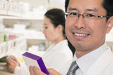 Photo: Portrait of smiling pharmacist holding prescription medication and looking at camera Portrait of smiling pharmacist holding prescription medication and looking at camera