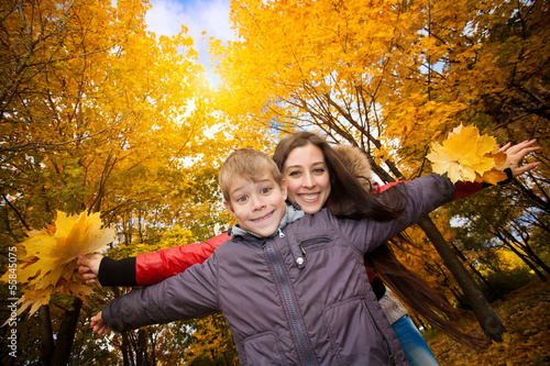 Photo: Mom and son are playing in a yellow autumn park Mom and son are playing in a yellow autumn park