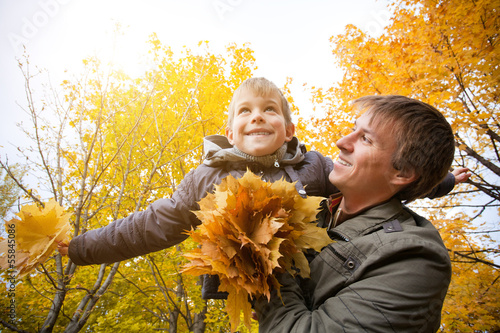 Photo: dad and son are playing in a yellow autumn park dad and son are playing in a yellow autumn park