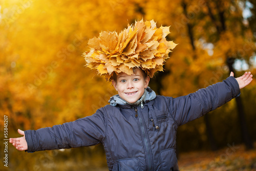 Photo: cheerful kid in a wreath on a autumn leafs background cheerful kid in a wreath on a autumn leafs background