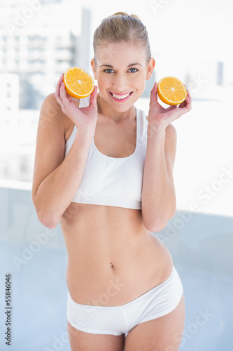 Photo: Gorgeous young blonde model holding two halves of an orange Gorgeous young blonde model holding two halves of an orange
