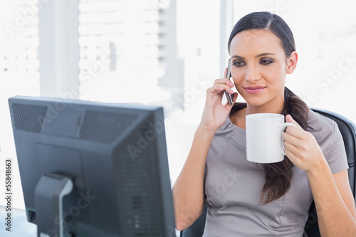 Photo: Attractive businesswoman holding coffee and answering phone Attractive businesswoman holding coffee and answering phone