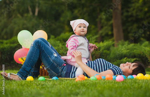 Photo: Happy mom and baby are playing in the park Happy mom and baby are playing in the park