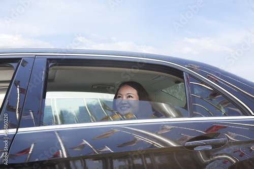 Photo: Young women in back seat of car looking out of window. Young women in back seat of car looking out of window.