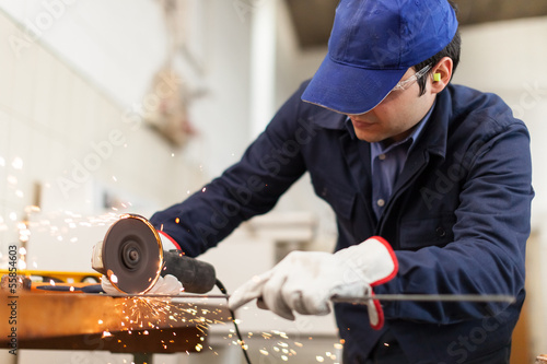 Photo: Worker grinding a metal plate Worker grinding a metal plate