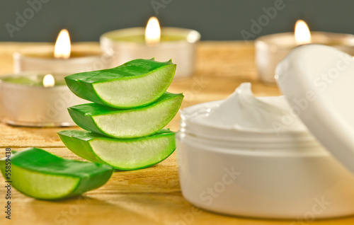 Photo: Fresh aloe vera slices and cream container on wooden. Fresh aloe vera slices and cream container on wooden.