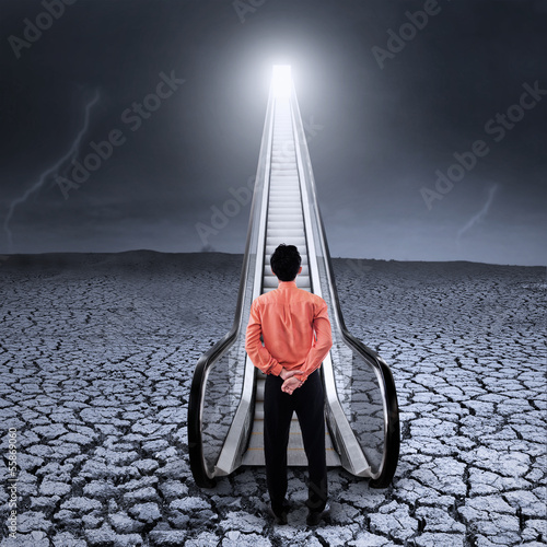 Photo: Businessman at escalator under cloudy sky Businessman at escalator under cloudy sky