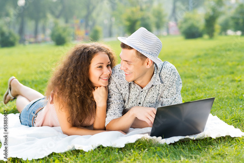 Photo: couple lying together in a park with laptop couple lying together in a park with laptop