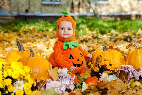 Photo: Child in pumpkin suit on background of autumn leaves Child in pumpkin suit on background of autumn leaves