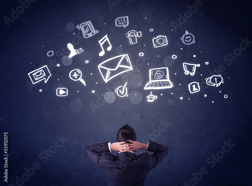 Photo: Businessman in chair with multimedia icons over his head Businessman in chair with multimedia icons over his head