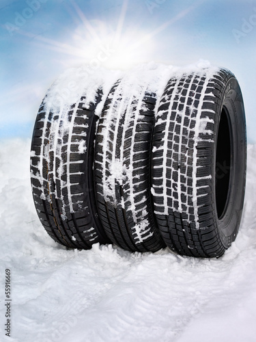 Photo: Snowy winter tyres in front of blue sky with sunlights Snowy winter tyres in front of blue sky with sunlights