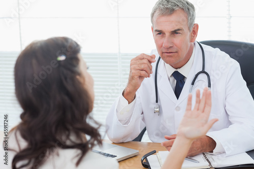Photo: Serious doctor listening to his patient talking Serious doctor listening to his patient talking