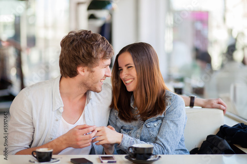 Photo: Candid image of young couple smiling in a coffee shop Candid image of young couple smiling in a coffee shop