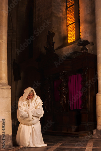 Photo: Kneeling monk in dark church Kneeling monk in dark church