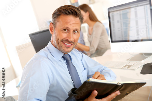 Photo: Portrait of handsome businessman holding agenda Portrait of handsome businessman holding agenda