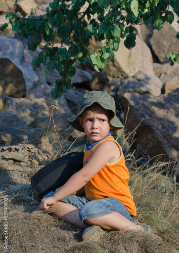 Photo: Young boy waiting alongside his rucksack Young boy waiting alongside his rucksack