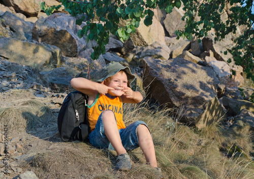 Photo: Cute little boy sitting on a mountain slope Cute little boy sitting on a mountain slope