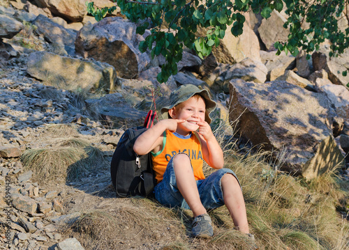 Photo: Cute little boy sitting on a mountain slope Cute little boy sitting on a mountain slope