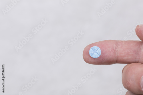 Photo: Fingers holding blue pill Fingers holding blue pill
