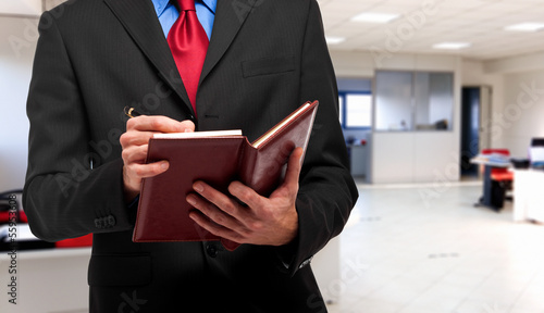 Photo: Businessman writing on his agenda Businessman writing on his agenda