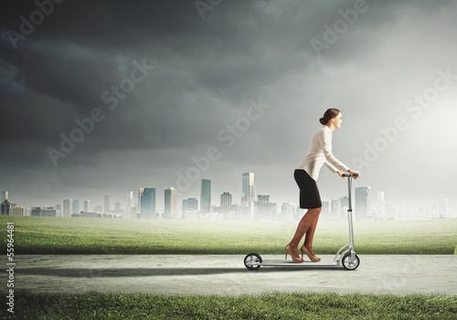 Photo: Businesswoman riding a scooter Businesswoman riding a scooter