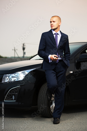 Photo: Young businessman with a cell phone at the car Young businessman with a cell phone at the car