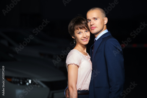 Photo: Young business couple against a car parking Young business couple against a car parking