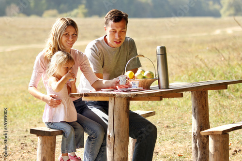 Photo: Young family having a picnic in nature Young family having a picnic in nature