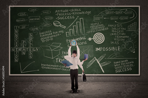 Photo: Businessman multitasking and business doodle on blackboard Businessman multitasking and business doodle on blackboard