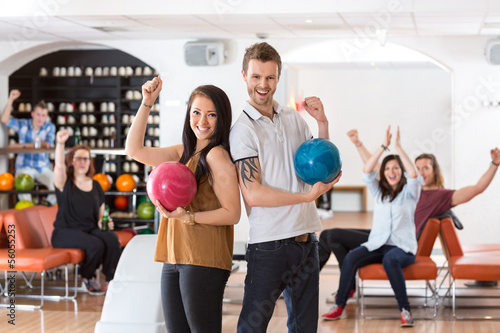 Photo: Excited Man And Woman With Bowling Balls in Club Excited Man And Woman With Bowling Balls in Club