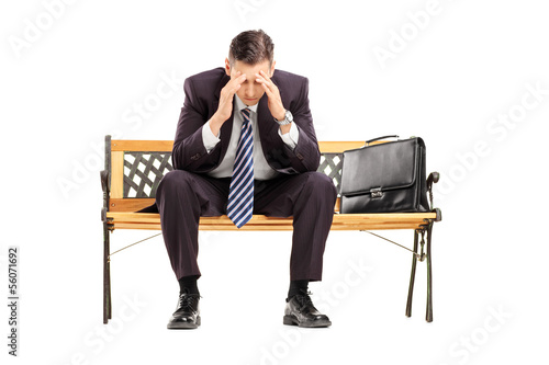 Photo: Disappointed young businessperson sitting on a wooden bench Disappointed young businessperson sitting on a wooden bench