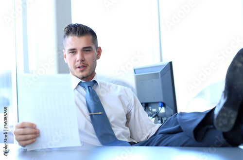 Photo: Happy businessman sitting in office Happy businessman sitting in office
