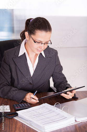 Photo: Happy young woman calculating finances Happy young woman calculating finances