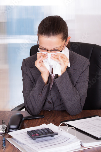 Photo: Sick young businesswoman blowing her nose Sick young businesswoman blowing her nose