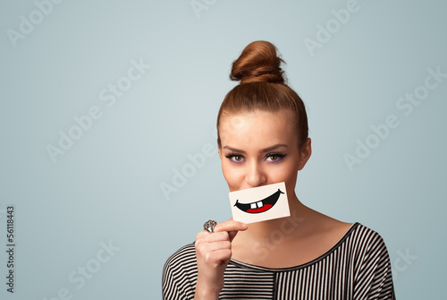 Photo: Happy pretty woman holding card with funny smiley Happy pretty woman holding card with funny smiley
