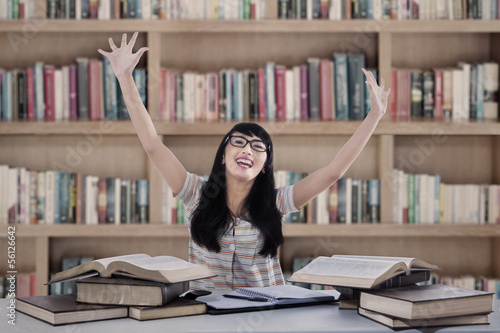 Photo: Excited female student at library Excited female student at library