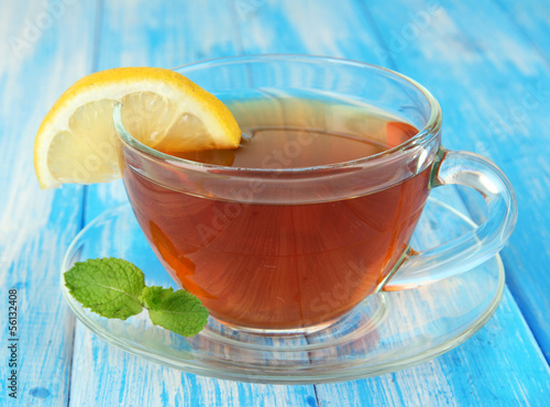 Photo: Cup of tea with lemon on table on blue background Cup of tea with lemon on table on blue background